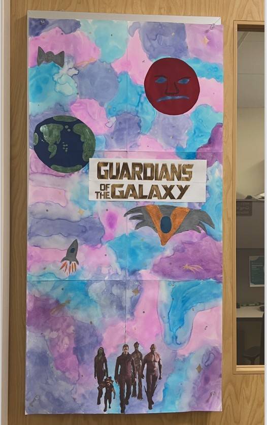 hand painted Guardians of the Galaxy sign with blue and purple and pink swirled background, the earth, a spaceship, and the main characters of the movie